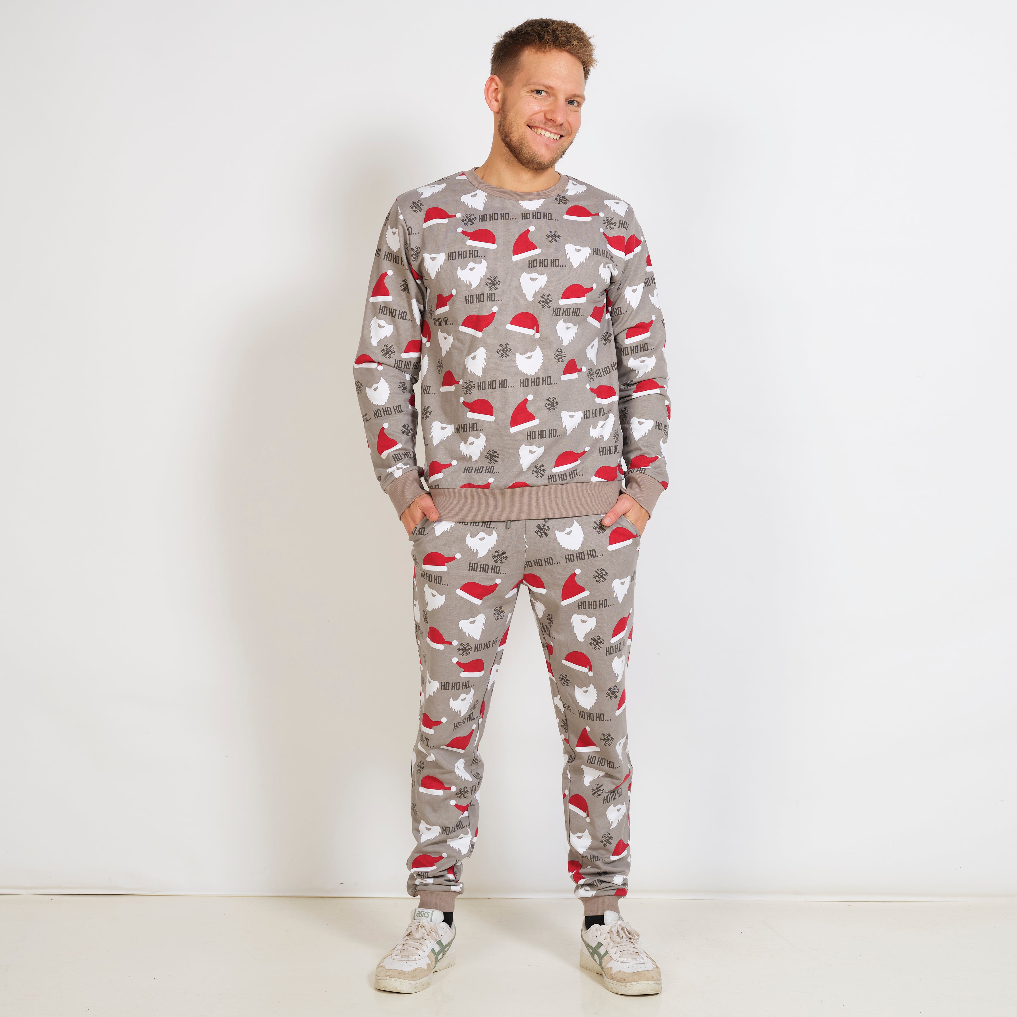 En mand iført en grå julesweatsuit med julemønster.